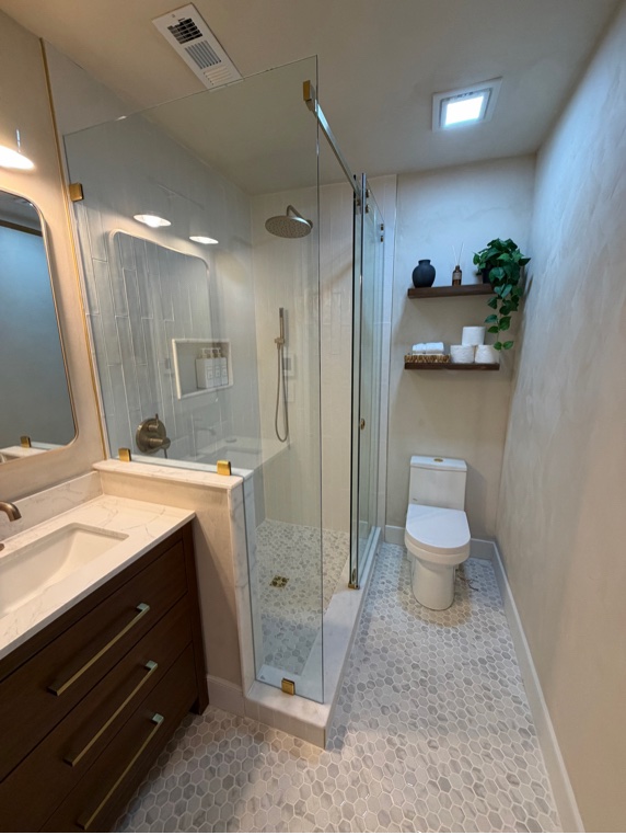 Bathroom after renovation, showing glass shower and modern toilet