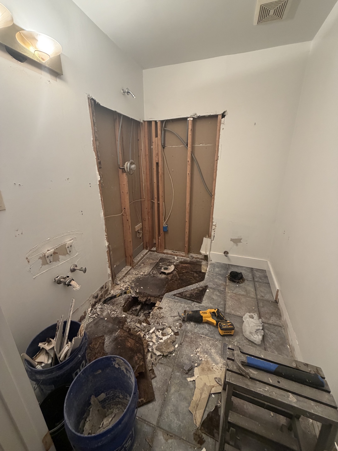 Bathroom during demolition with damaged floor exposed beneath the shower