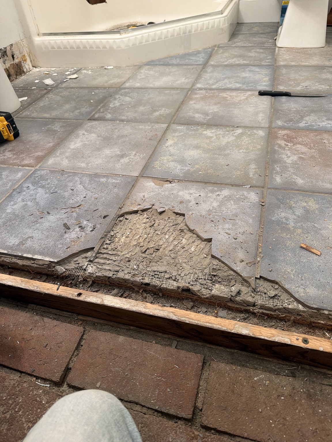 Old bathroom floor raised above the brick hallway floor